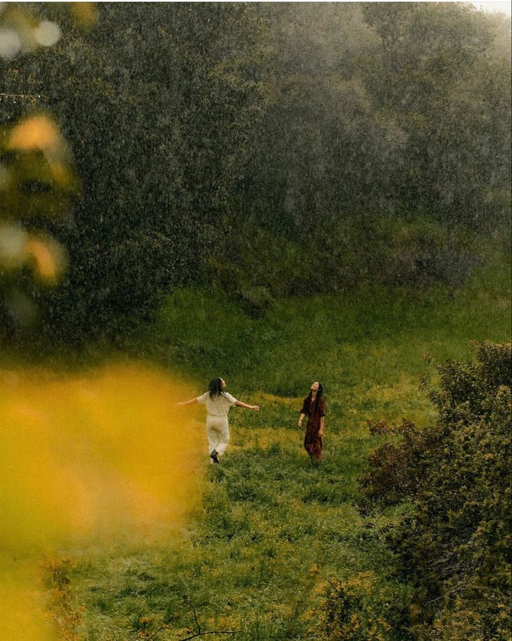 Two women moving freely through a field in the rain